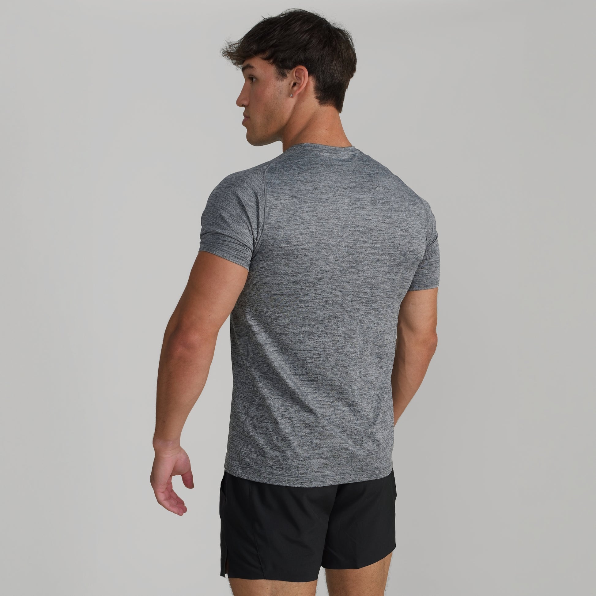 Male model wearing GIGA Base Tee in grey, back view showing fit across shoulders