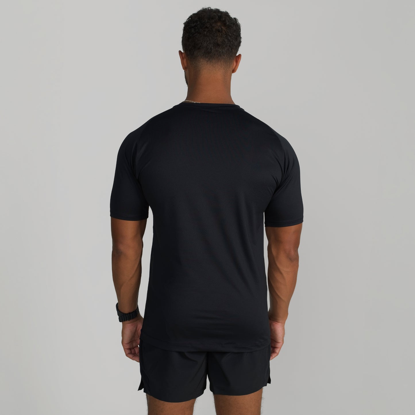 Male model wearing GIGA Base Tee in black, back view showing fit across shoulders