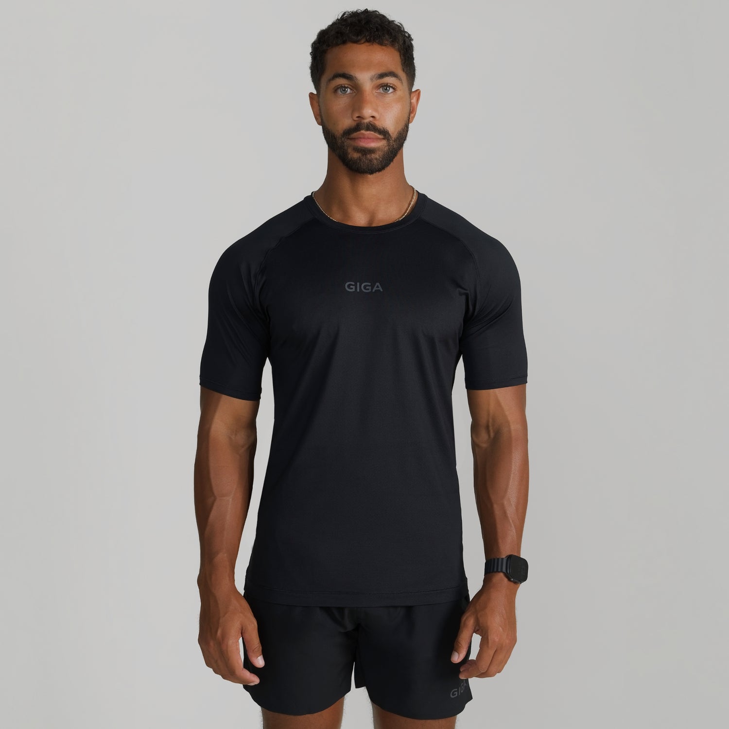 Male model wearing GIGA Base Tee in black, front view, slim fit athletic t-shirt
