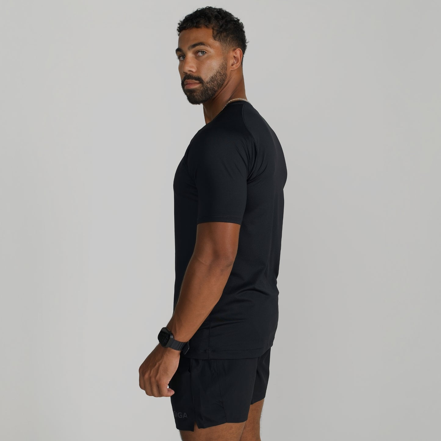 Male model wearing GIGA Base Tee in black, side profile showing tapered fit