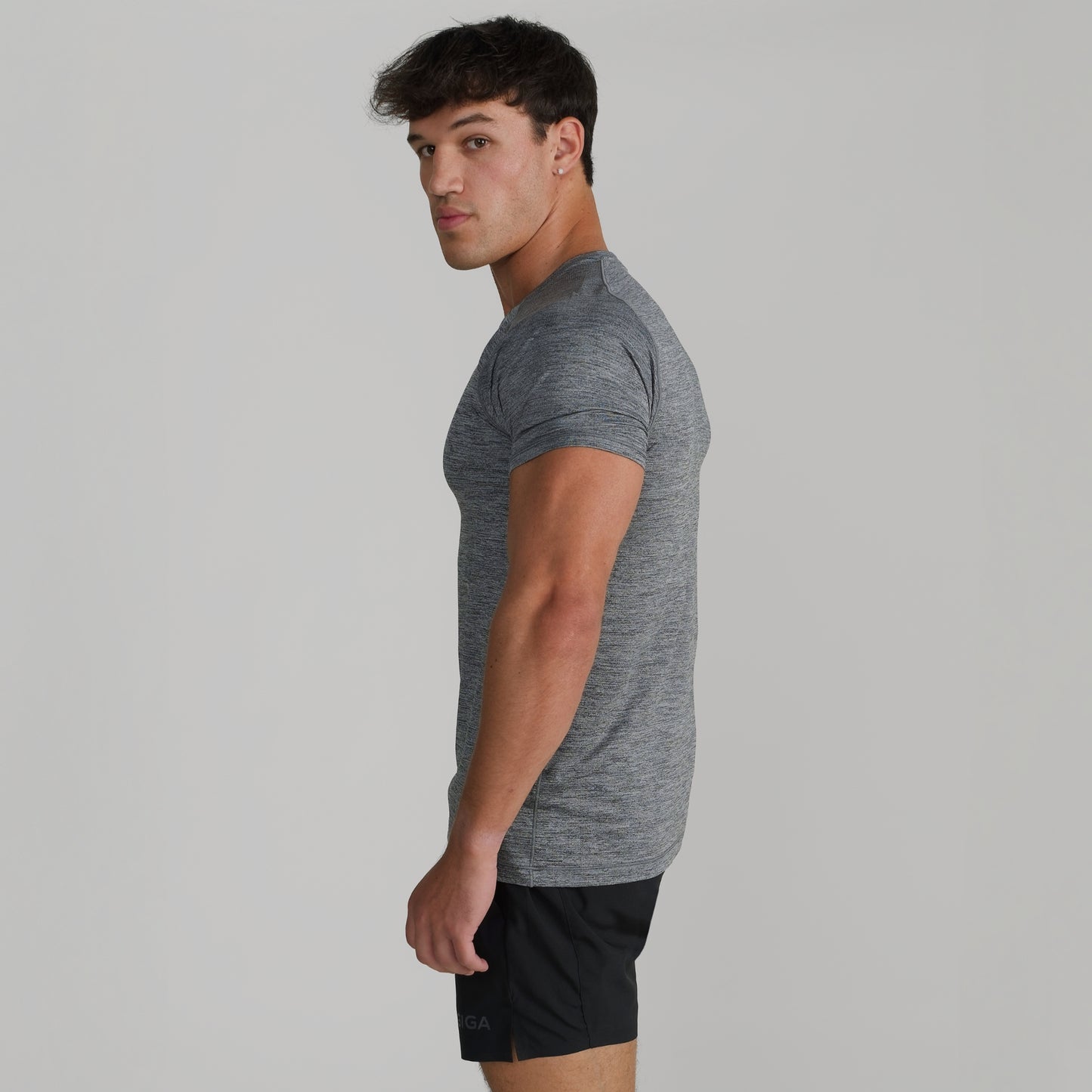 Male model wearing GIGA Base Tee in grey, side profile showing tapered fit