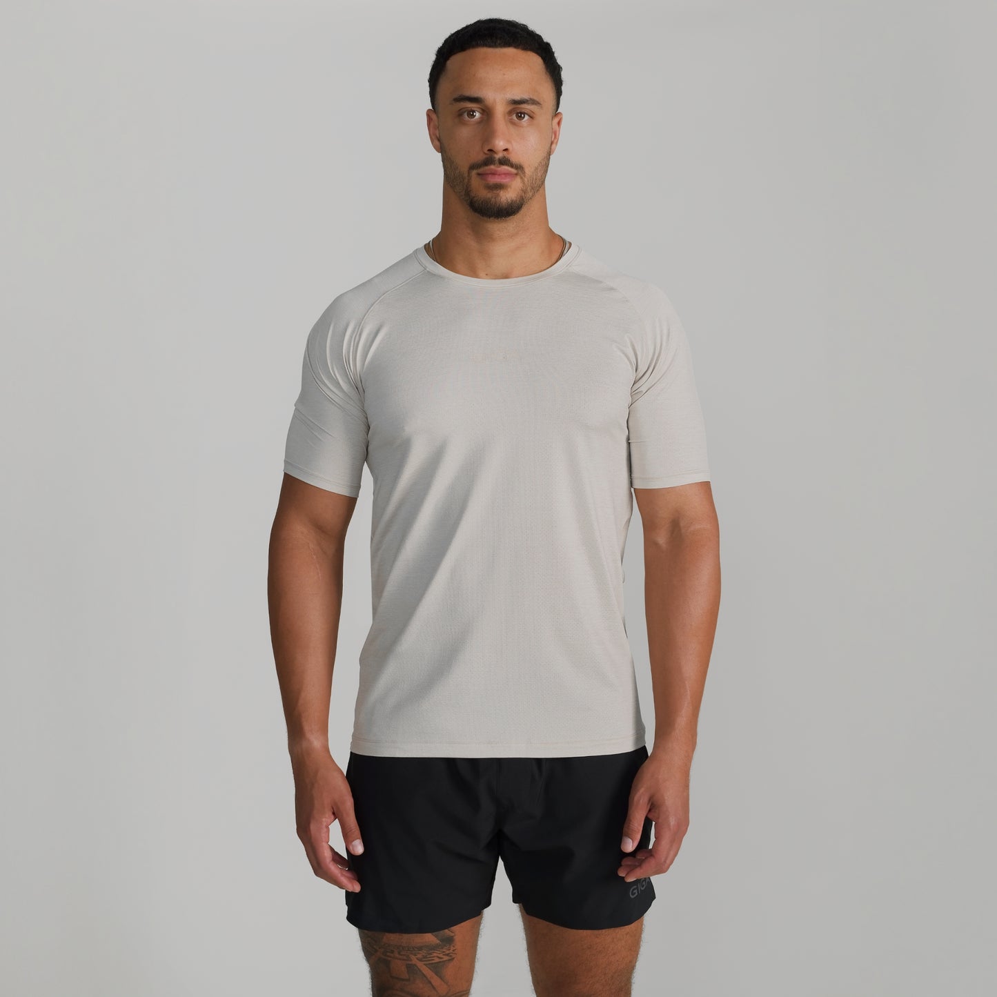 Male model wearing GIGA Base Tee in white, front view, slim fit athletic t-shirt