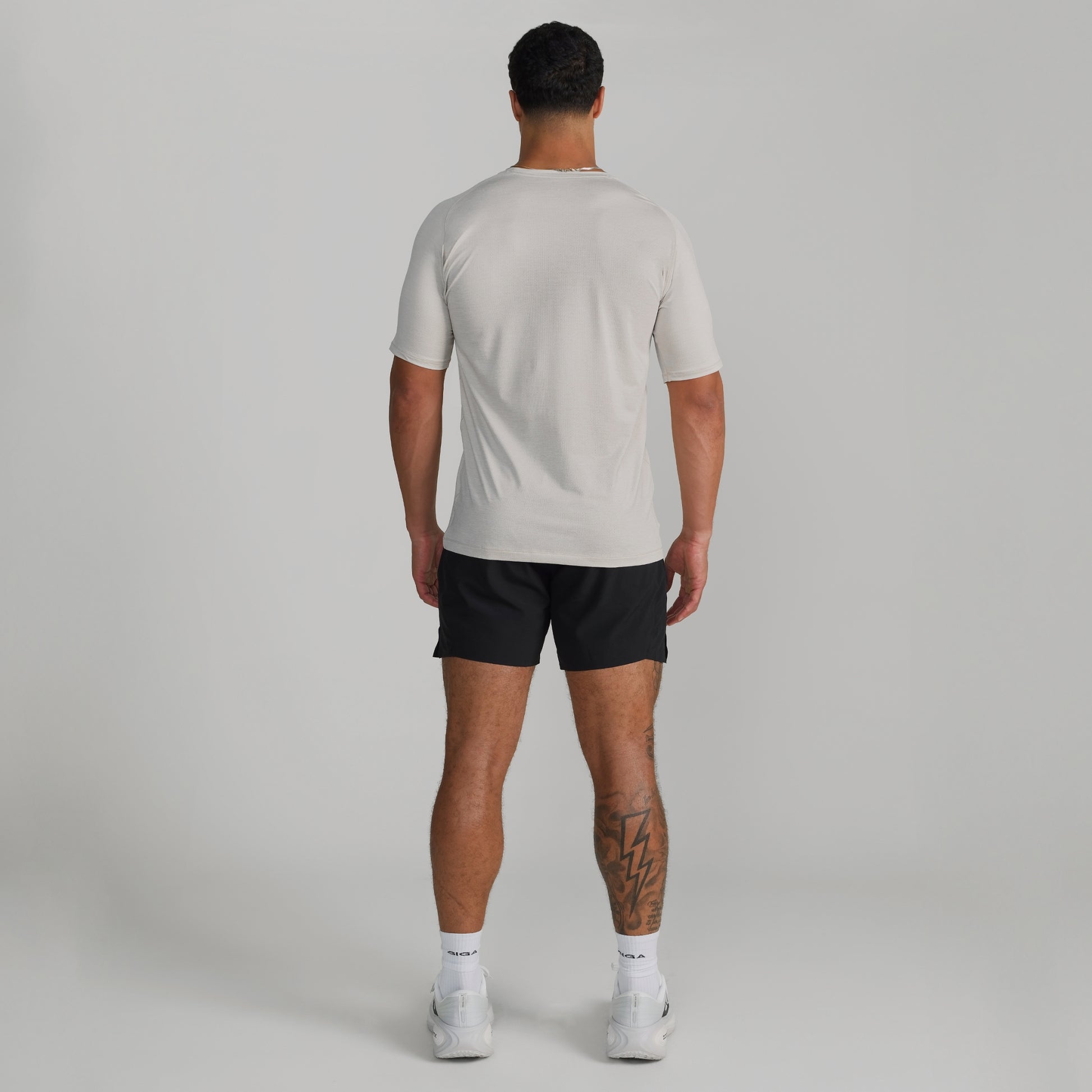 Male model wearing GIGA Base Tee in white, back view showing fit across shoulders