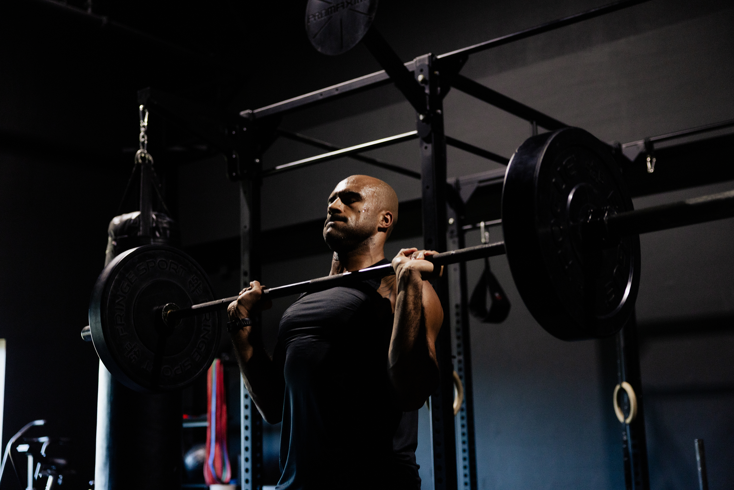 Man performing barbell squat in gym wearing GIGA Core Tank