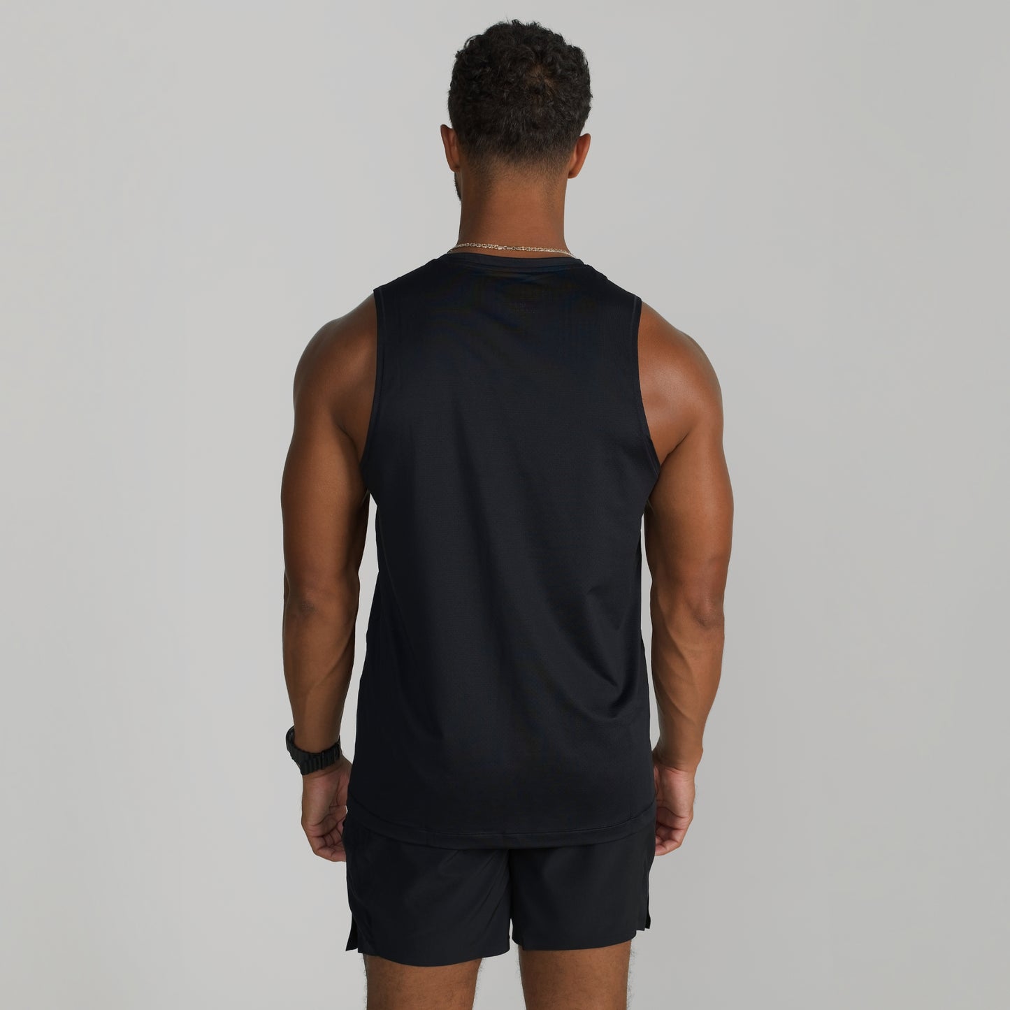 Male model wearing GIGA Core Tank in black, back view showing fit across shoulders