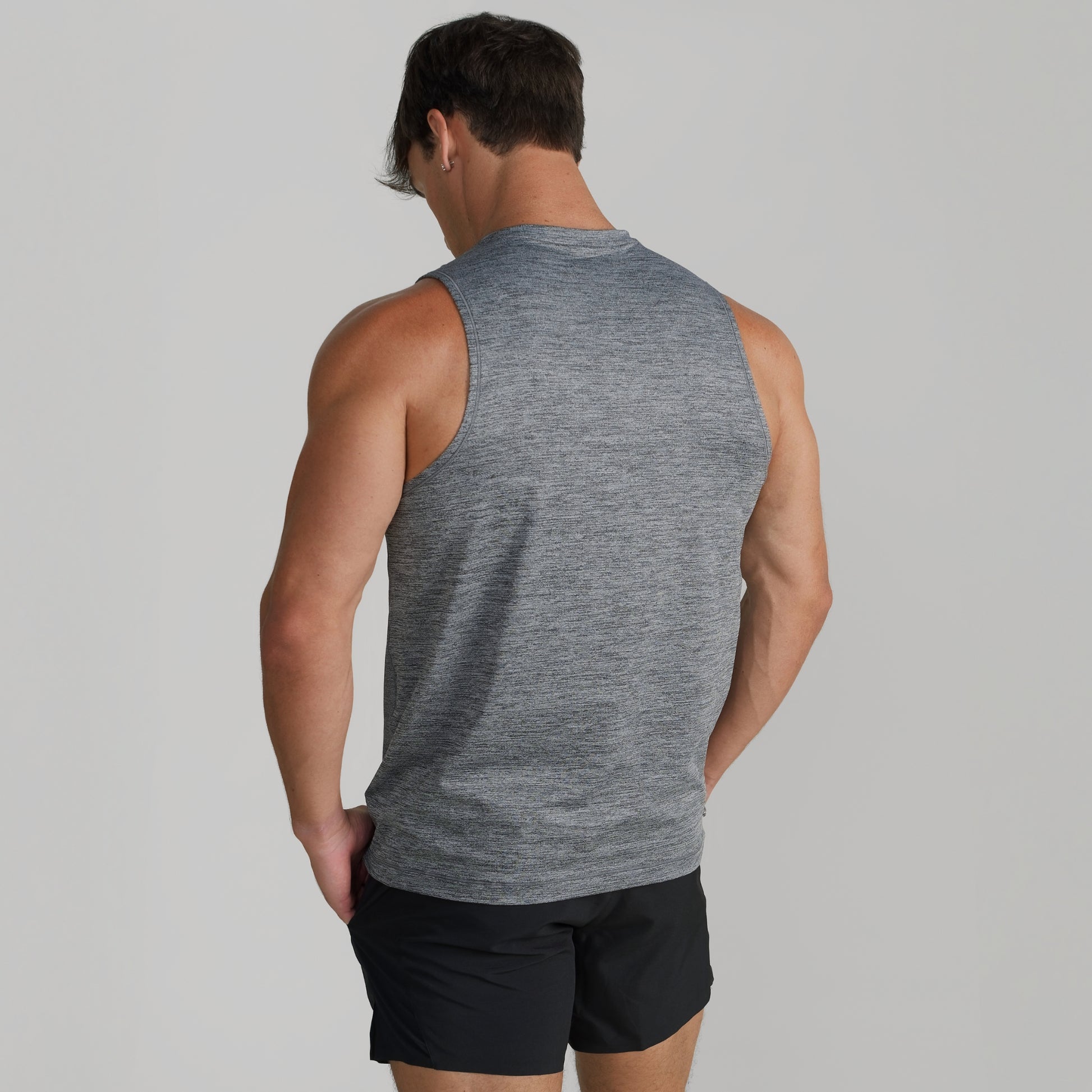 Male model wearing GIGA Core Tank in grey, back view showing fit across shoulders