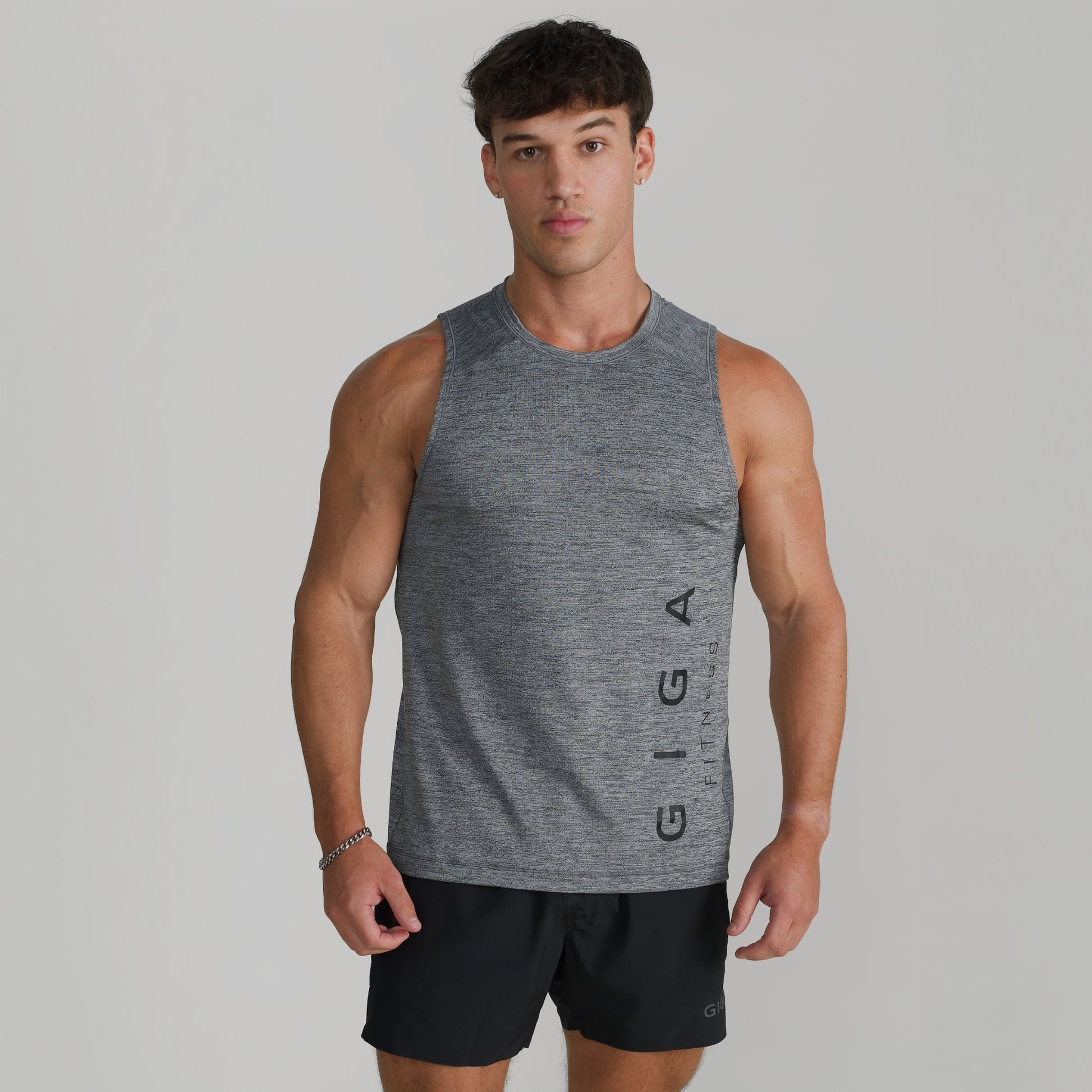 Male model wearing GIGA Core Tank in grey, front view, slim fit athletic tank top