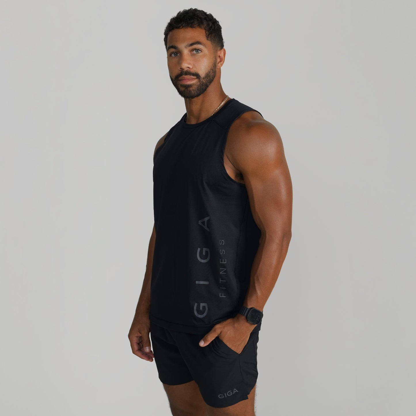Male model wearing GIGA Core Tank in black, side profile showing armhole and tapered fit