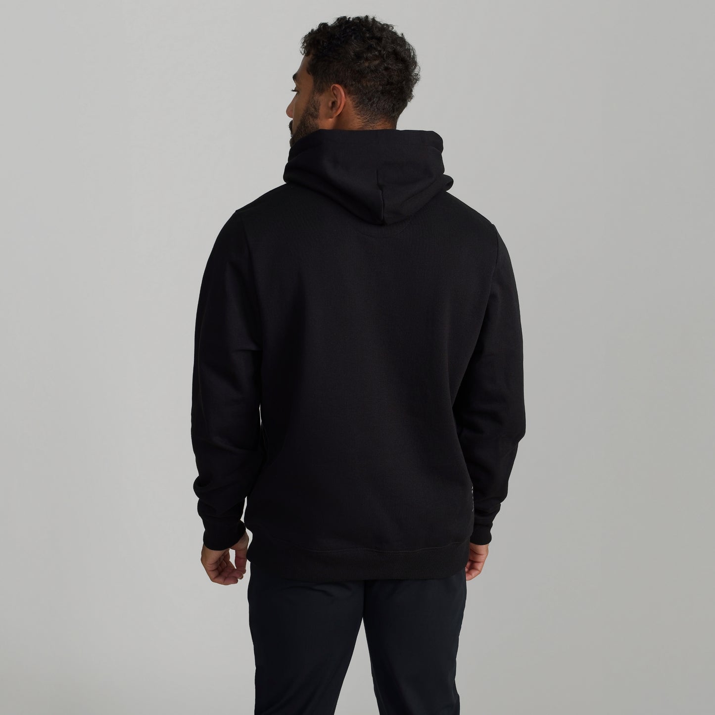 Man wearing GIGA Recovery Hoodie in black back three quarter view upper body