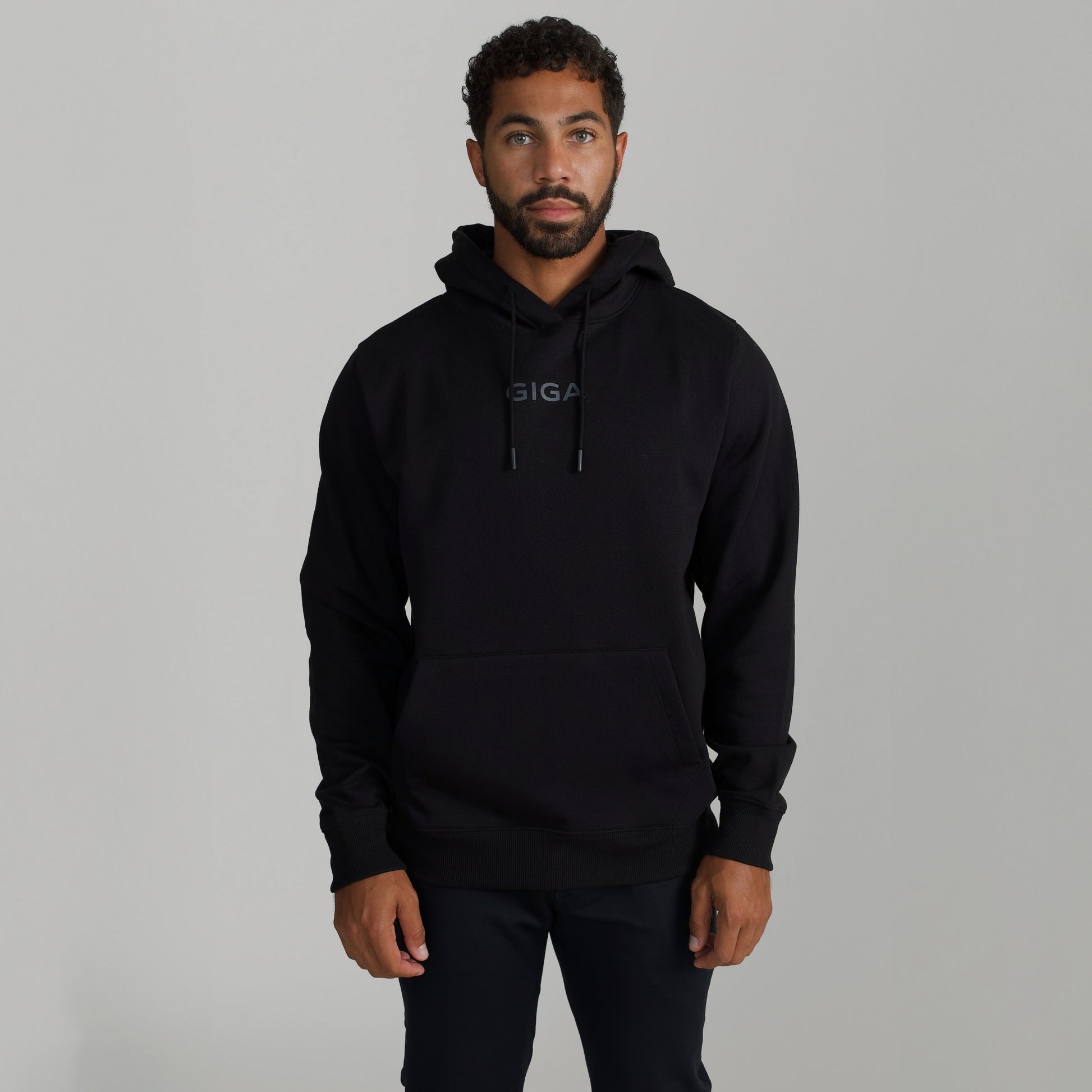Man wearing GIGA Recovery Hoodie in black front view arms down upper body