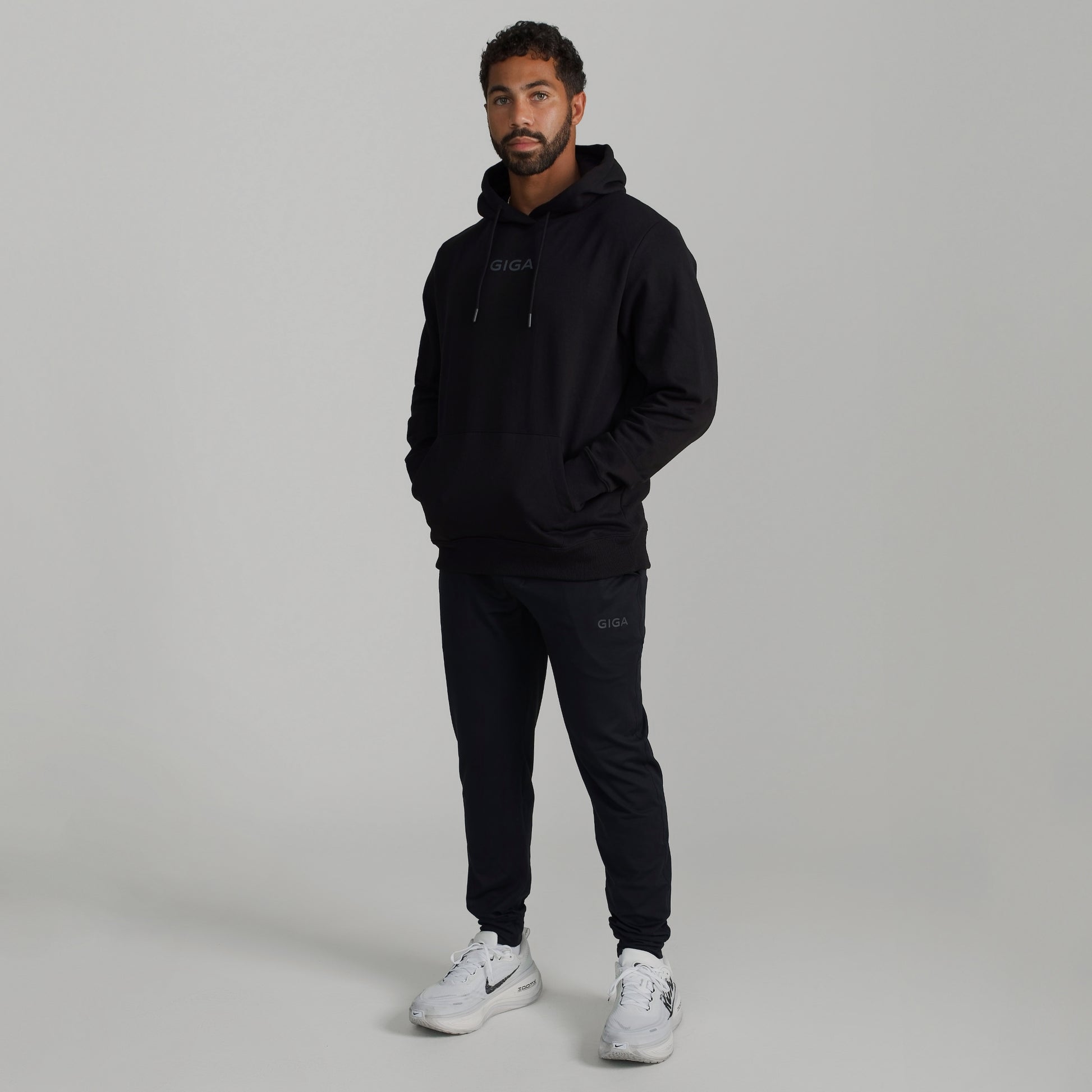 Man wearing GIGA Recovery Hoodie in black front view hands in pocket